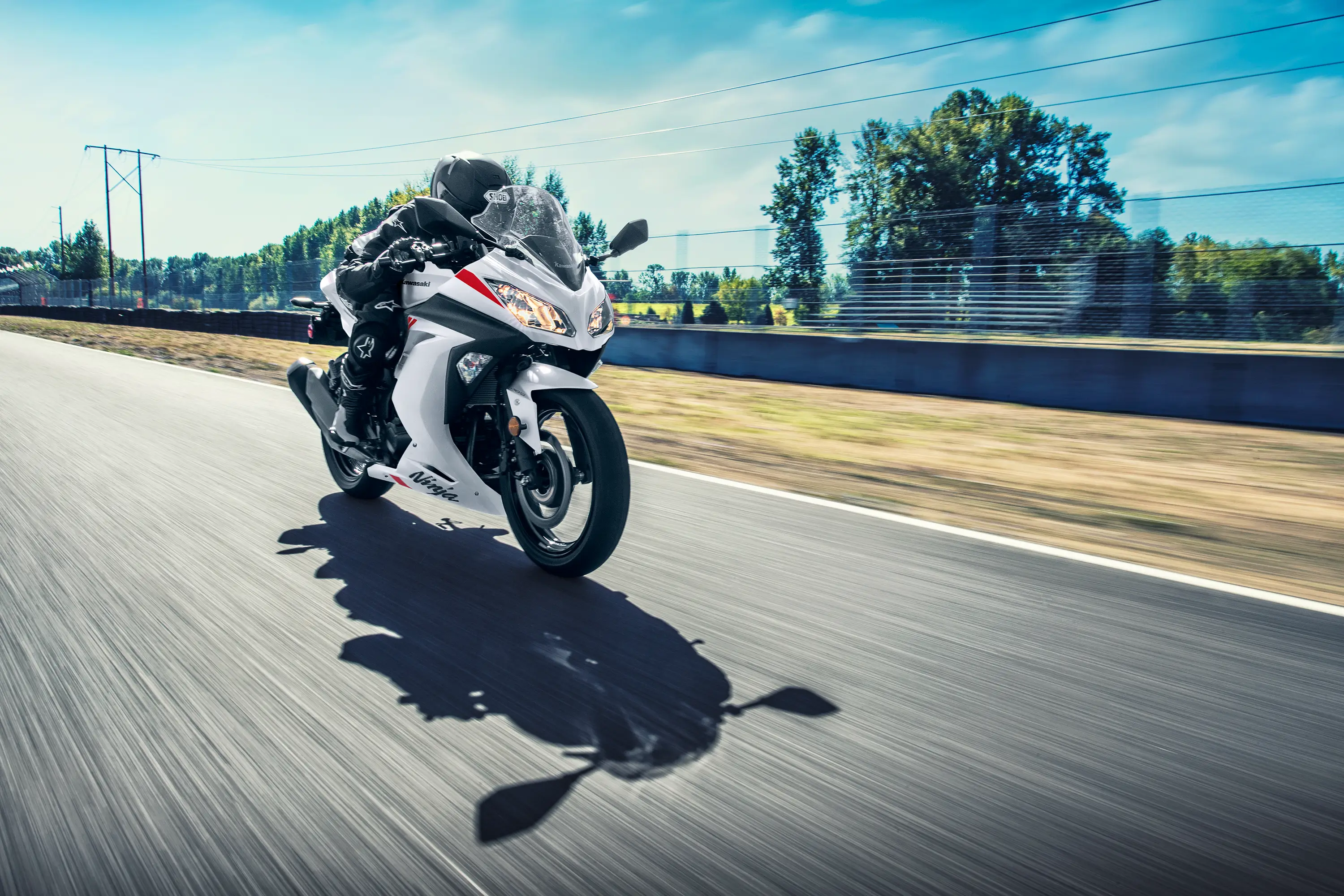 Three-quarter front angle of a person riding a white motorcycle on a track.