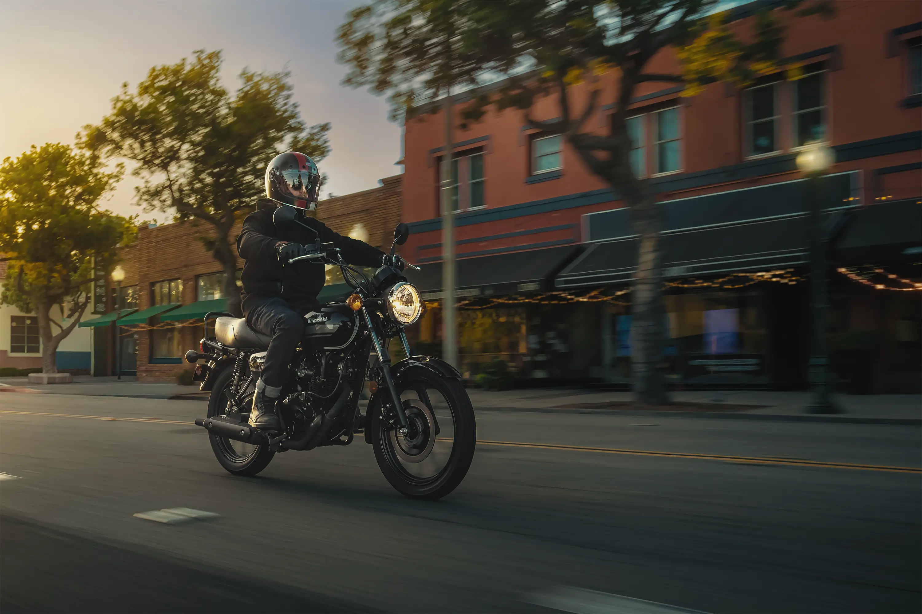 Three-quarter front angle of a person riding a motorcycle on a downtown street.