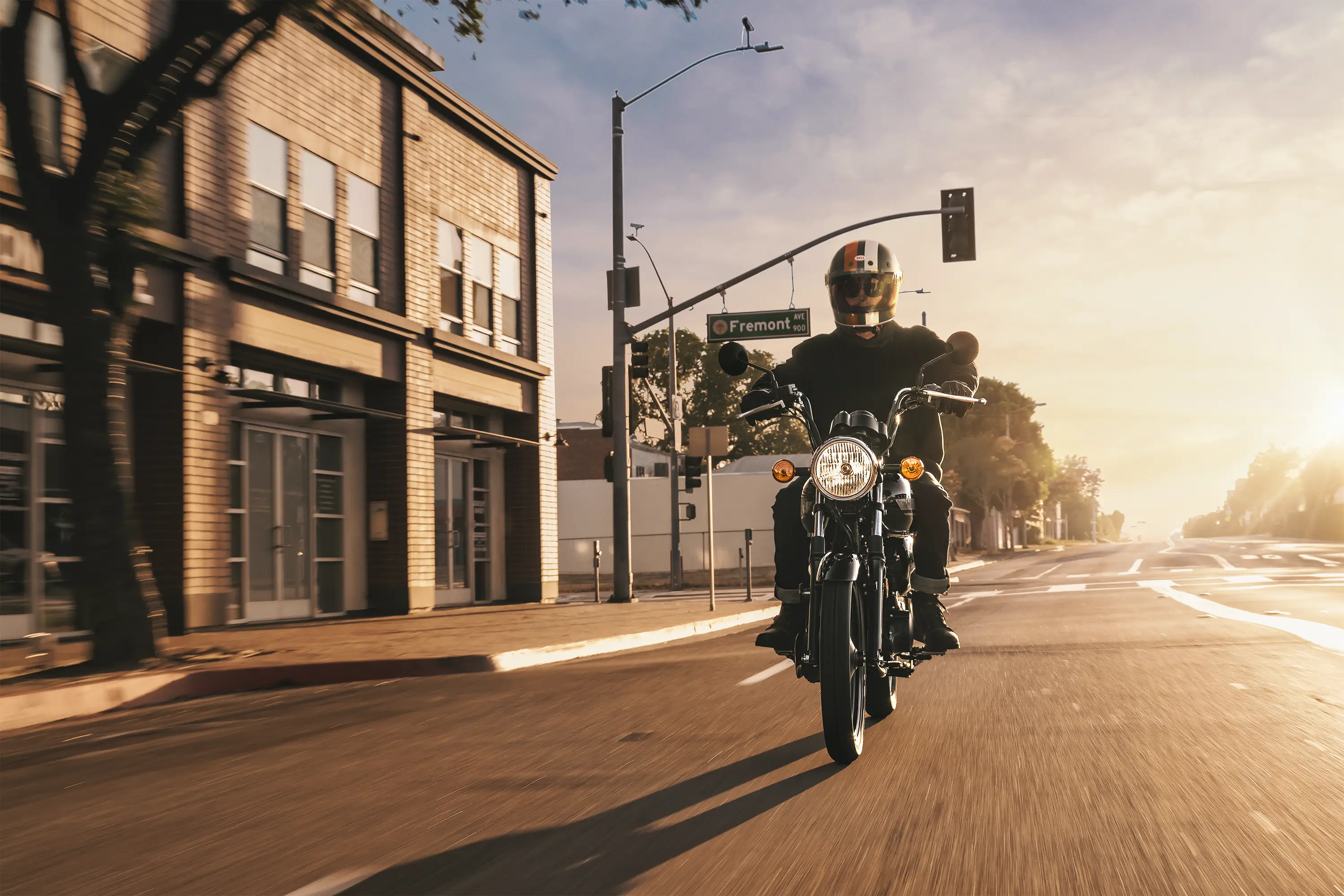 Front angle of a person riding a motorcycle down a street.