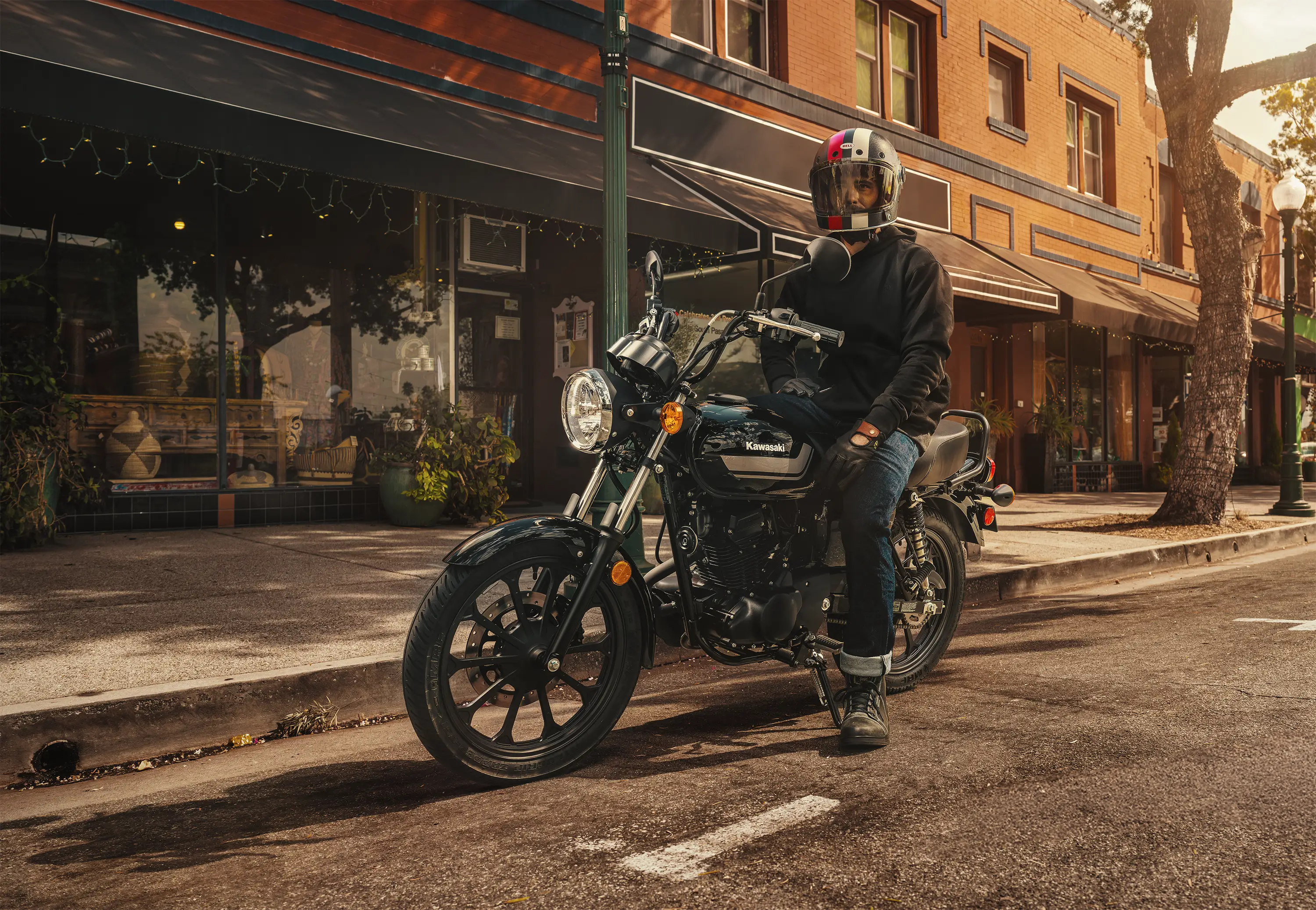 Three-quarter front angle of a person seated on a motorcycle parked in a downtown area.