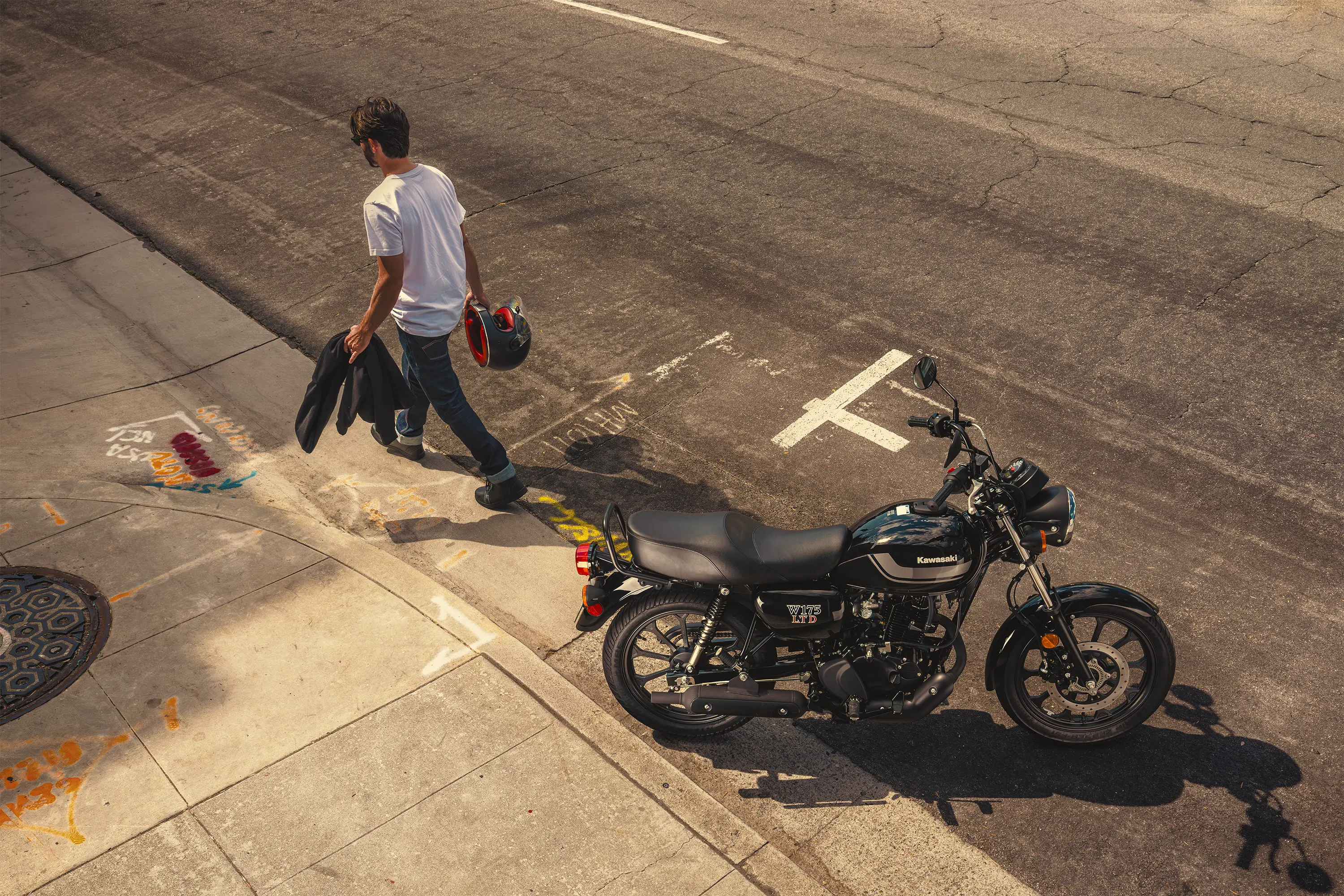 Aerial side angle of a person walking near a motorcycle parked in a downtown area.