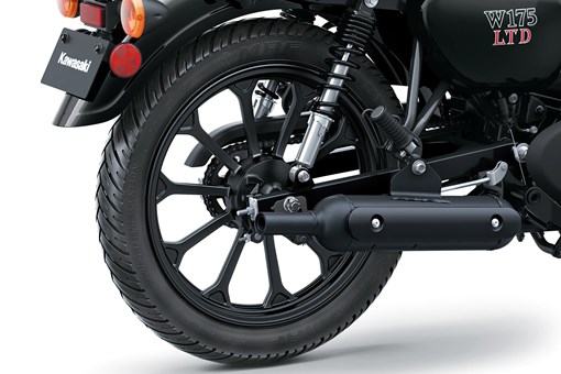 Close-up of the rear wheel and exhaust of a motorcycle staged in a white studio background. opens in a new window