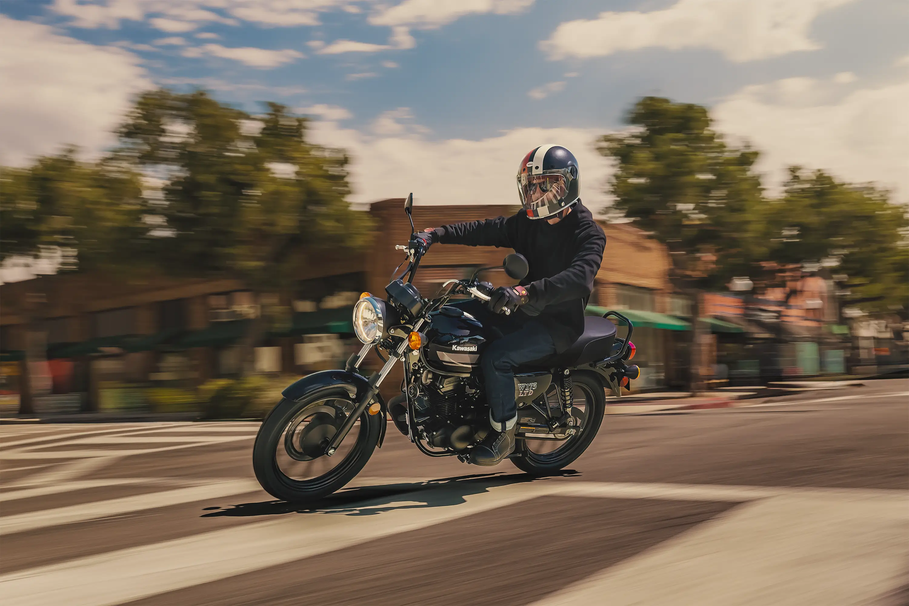 Side angle of a person riding a motorcycle in a downtown area.