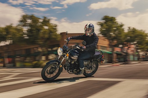 Side angle of a person riding a motorcycle in a downtown area. opens in a new window