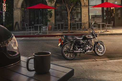 Side angle of a motorcycle parked on the street in a downtown area. opens in a new window