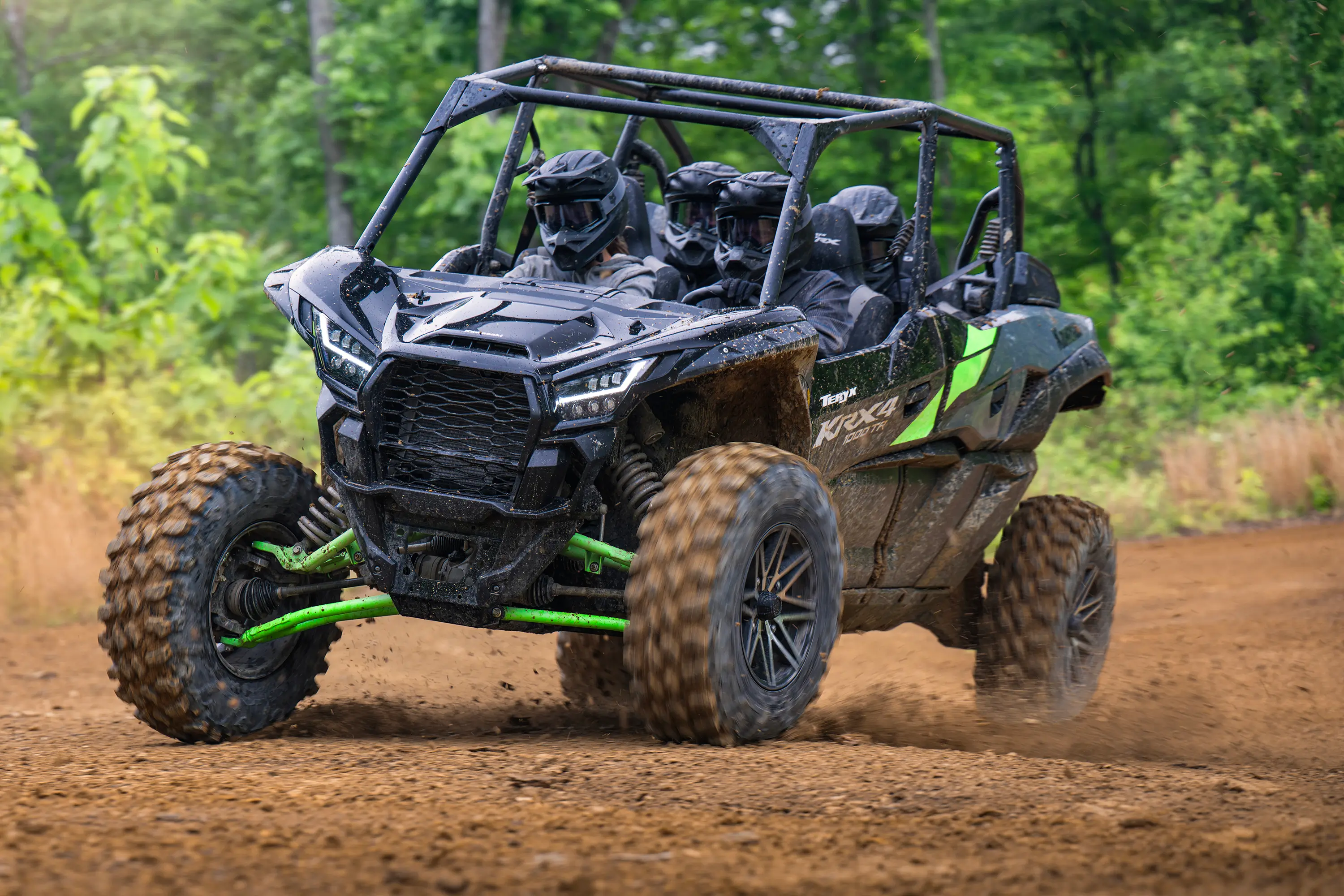 Three-quarter front angle of a driver and passengers in a side x side riding on a wooded trail.